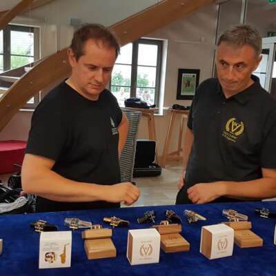 Two caucasian men looking at clarinet or saxophone ligatures and mouthpieces